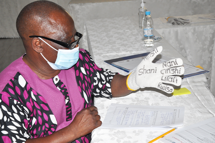 "Participant in the Zambia TTE project wearing a glove with words written on the palm and fingers"