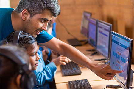 "Bhushan Dahal working with children in front of a computer"