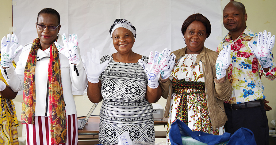 "Four teachers standing displaying white gloves with lots of writing on their hands."