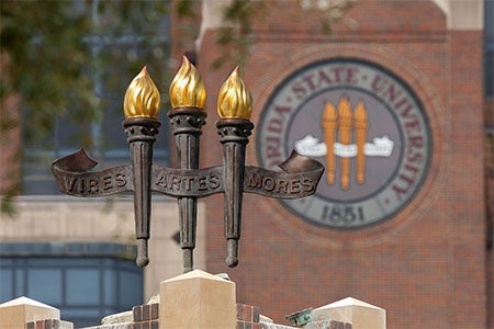 FSU campus building with the university seal in stained glass and a fountain with the three torches.
