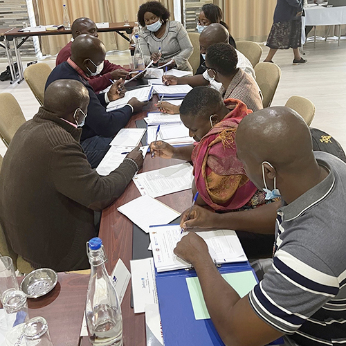 "Group sitting at a long table at a Province level meeting for the Transforming Teacher Education project in Zambia"