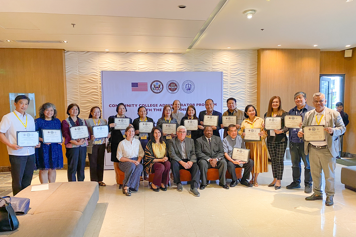 "Large group holding certificates posing in front of a sign for the CCAP"