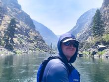 Dr. Rob Schoen posing for a photo in a boat on a lake with mountains behind him.