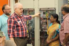 Man standing in front of panel with wires talking to a CCAP India visitors