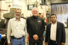 Three men posing for a photo inside a machine shop