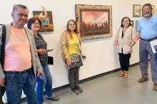 Small group posing in front of a painting 