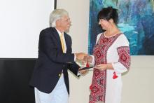 A woman being presented a certificate and shaking hands with the presenter