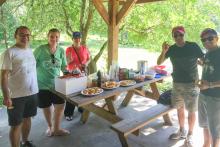 Small group of people around a picnic table with food