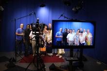 Photo of the CCAP Ukraine group in a media studio projected onto a screen next to a video camera. 