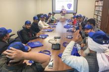 CCAP Pakistan group around a table wearing blue hats with the Santa Fe Institute of Public Safety logo