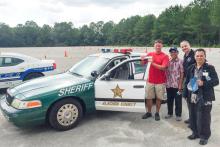 Four men standing next to an Alachua County Sheriff patrol car