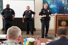 Three law enforcement officers are addressing a group