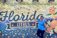 A member of the CCAP South Africa group posing in front of a wall with a Florida citrus painting at Disney Springs