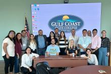 CCAP Mexico group photo in front of a large screen with the logo for Gulf Coast State College