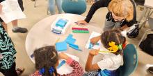 Teacher working with two you students at a table.