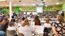 Large classroom with people looking at a demonstration at the front of the room