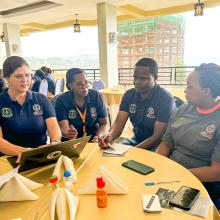 Small group at a table working around a laptop at the USAID Tunoze Gusoma (Schools and Systems) activity in Rwanda.