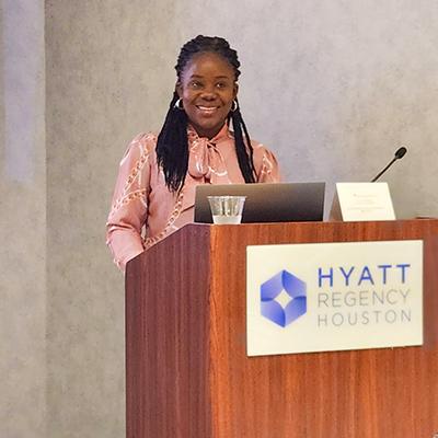 Dr. Brenda Wawire at a conference presenting at a podium.