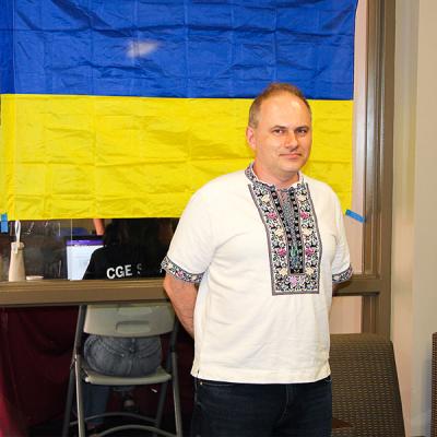 Dr. Taras Panchenko standing in front of a Ukraine flag.