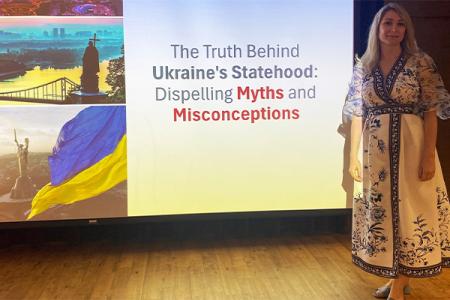 Dr. Anna Romanova on stage in front of a projection screen during a lecture sponsored by FSU's Ukraine Task Force